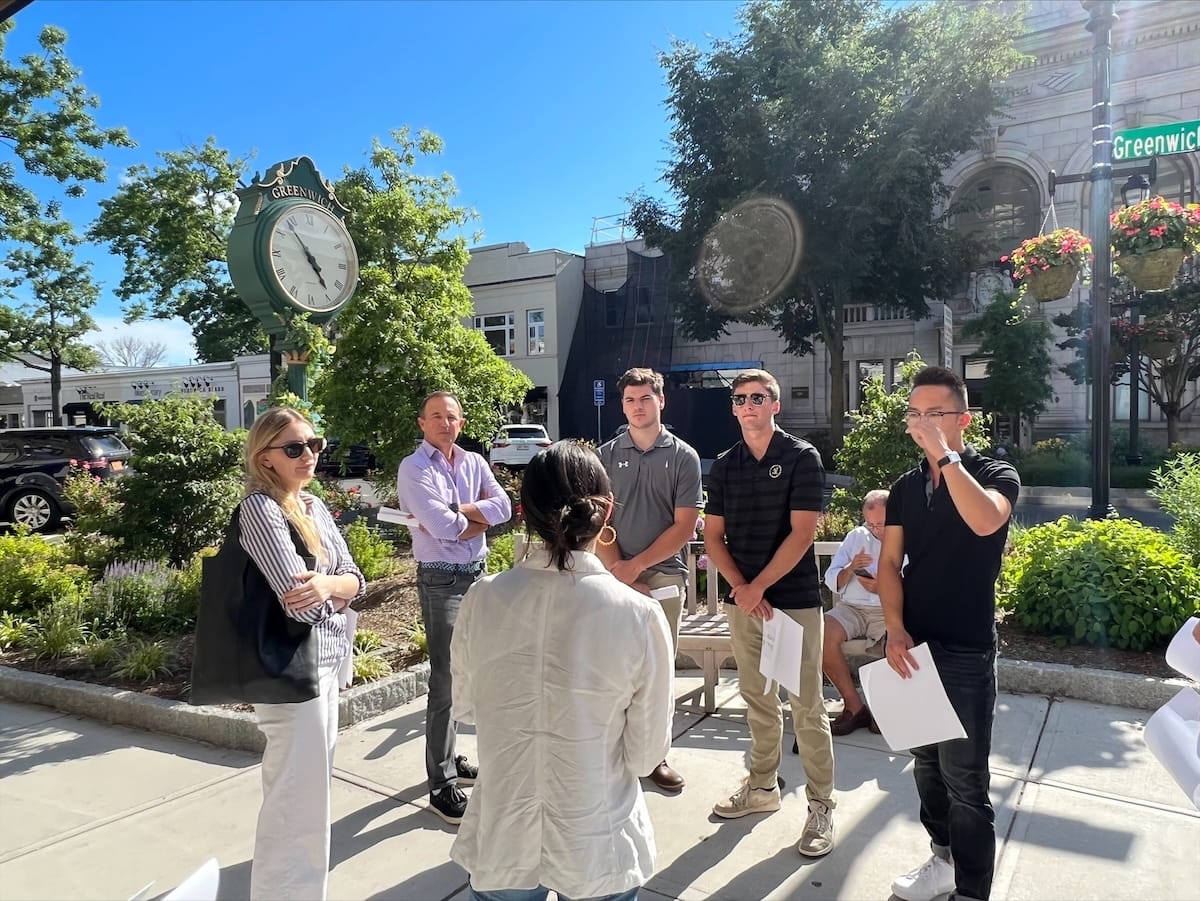 Group of people standing outdoors in a town square.